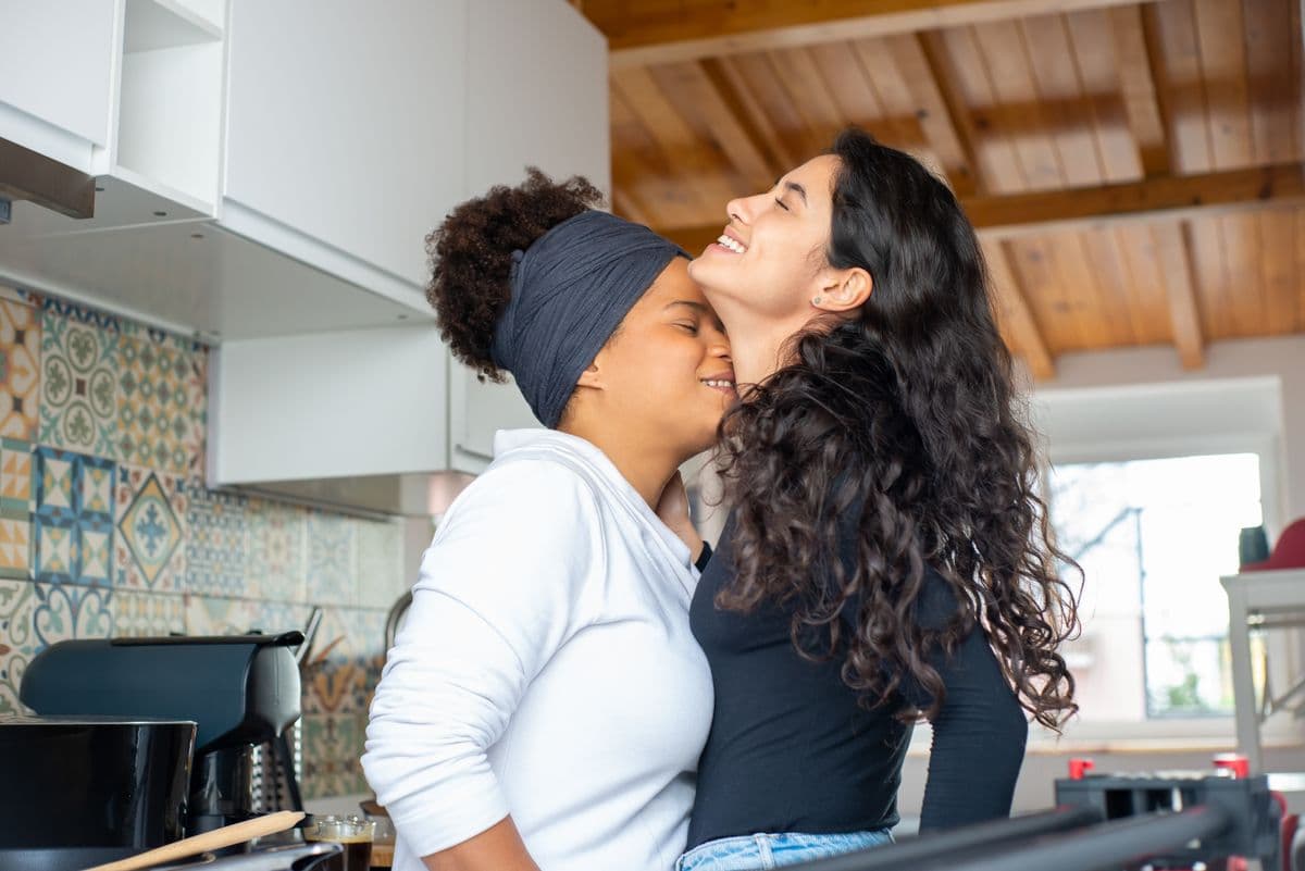 Deux femmes enlacées, complices, dans leur cuisine